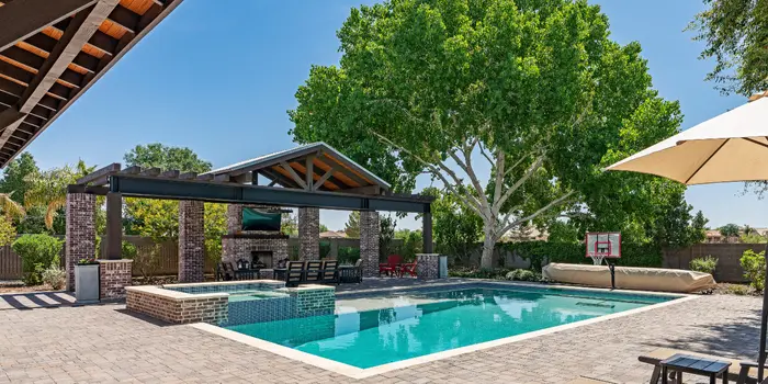 Infinity edge fibreglass pool with blue mosaic tiles overlooking a panoramic sunset valley view from a hillside deck.